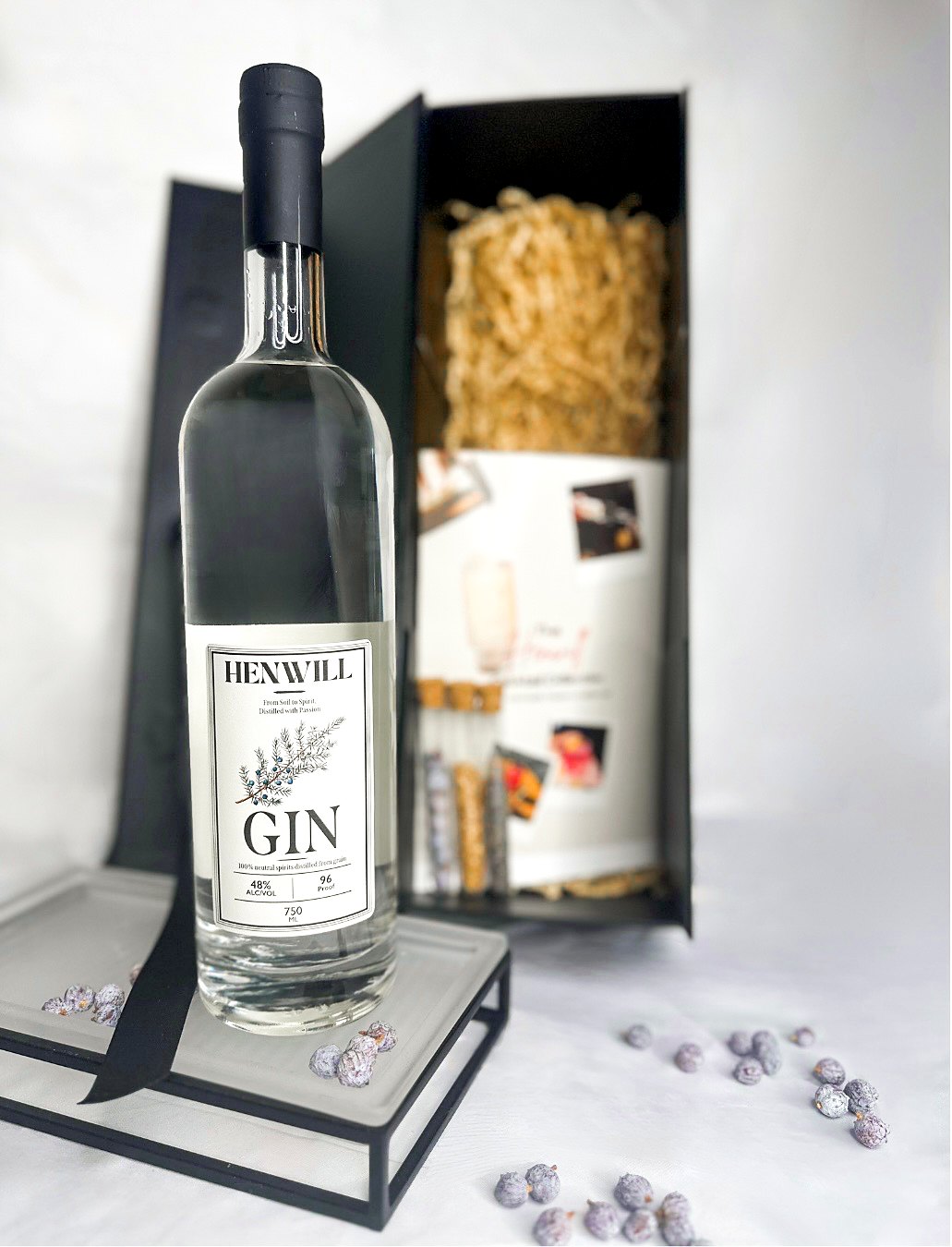 The Henwill Experience: a Henwill Gin bottle beside an open black keepsake box with botanicals and a booklet